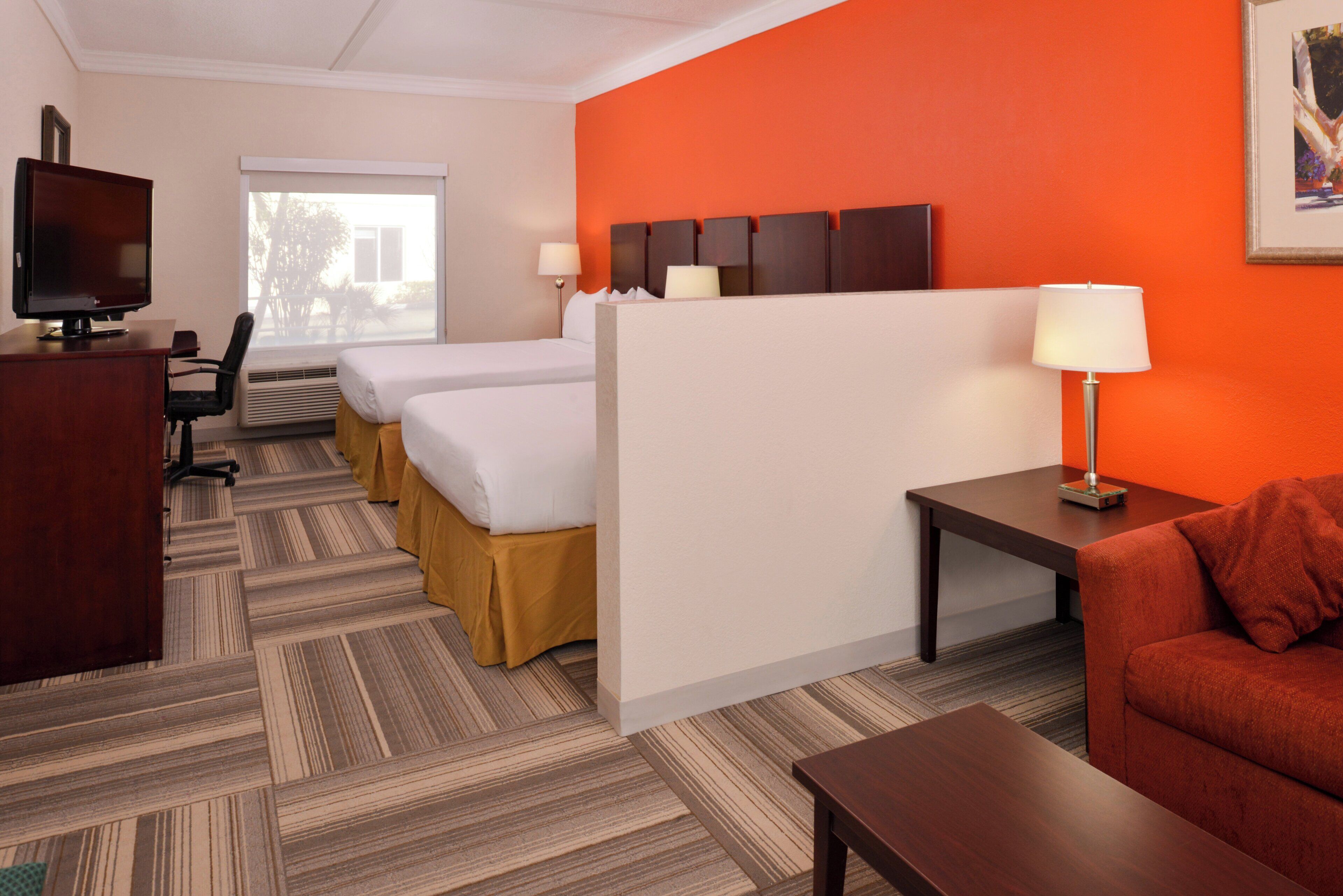 Ein Hotelzimmer mit einem Bett, einem Schreibtisch, einem Sessel, einem Fernseher und einem Fenster.