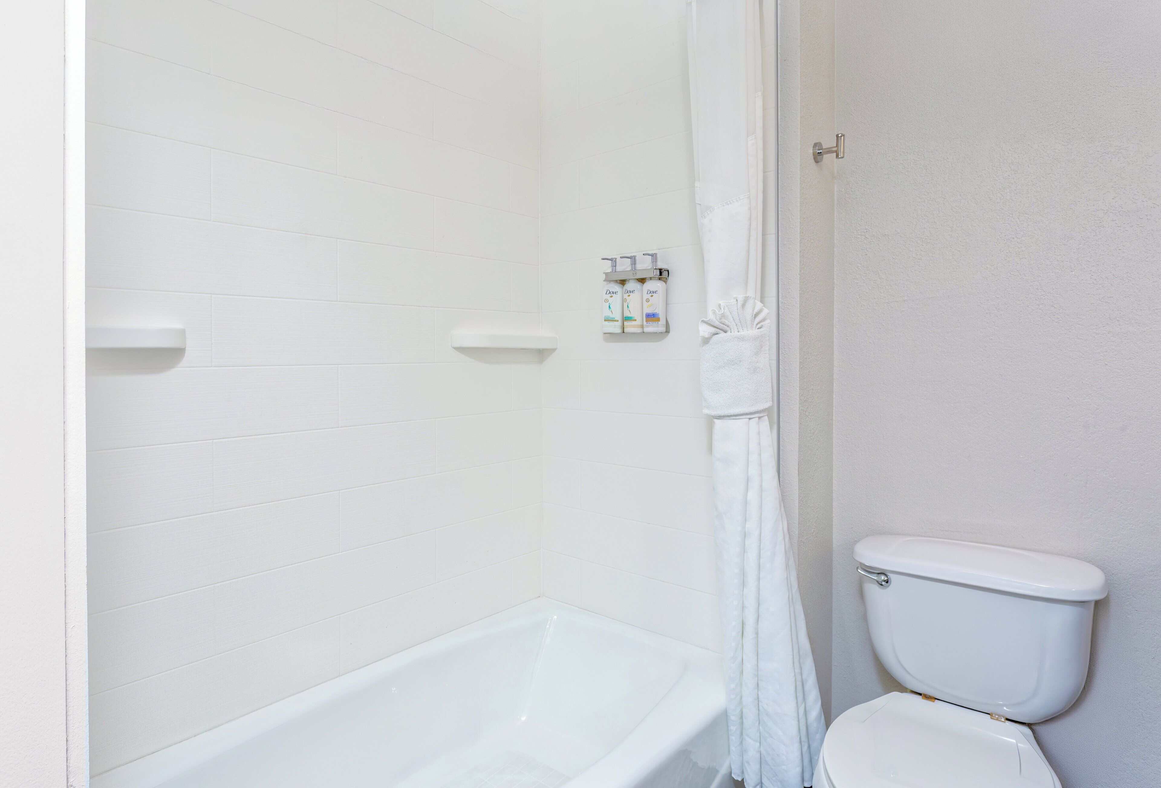 Un baño con una bañera blanca, un inodoro y una cortina de ducha.