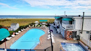 Un área de piscina con jacuzzi, sillas de descanso y vistas a la playa.