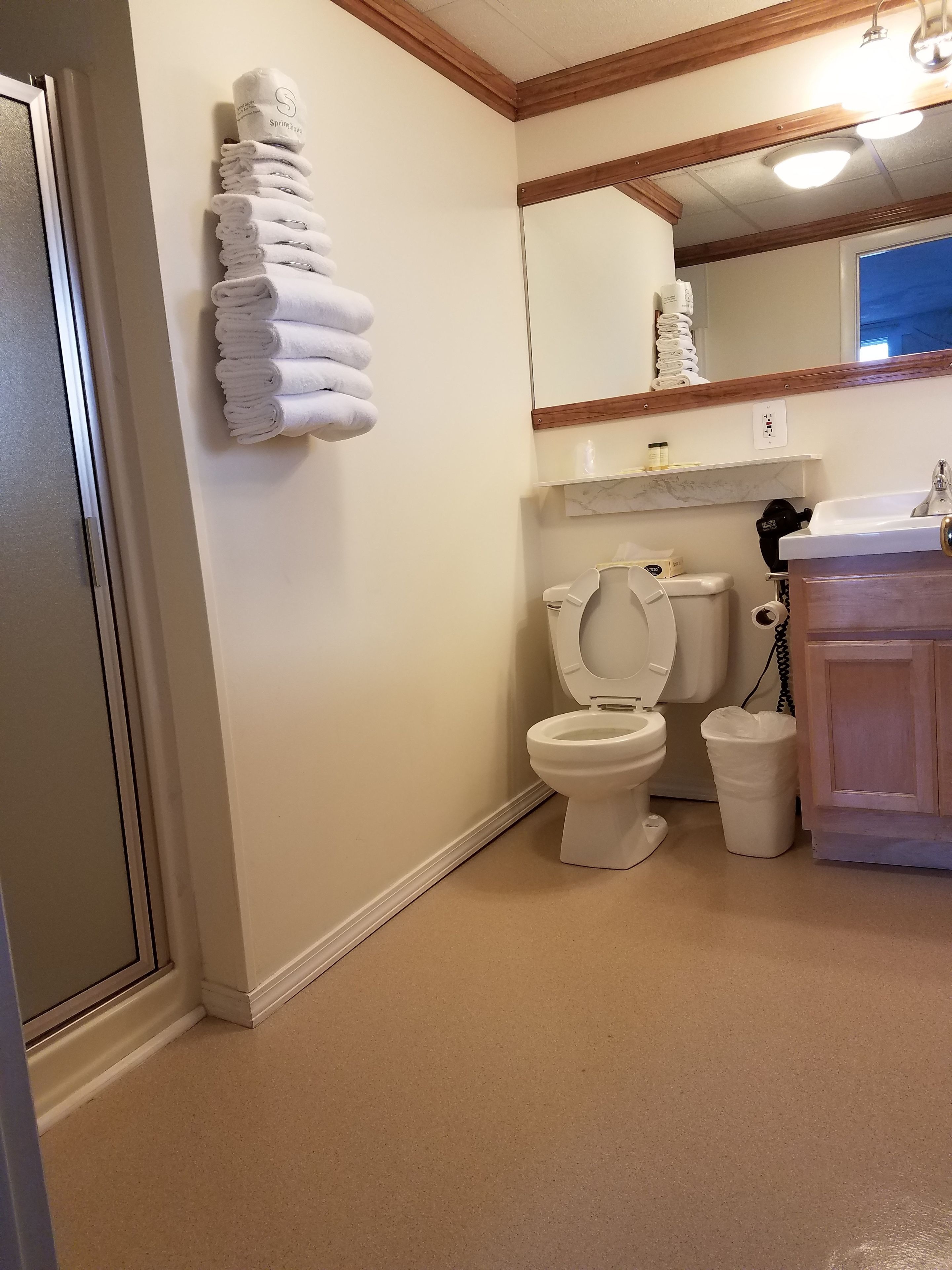 A bathroom with a toilet, sink, and stacked towels on the wall.