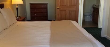 Una cama bien hecha en una habitación de hotel con un aparador de madera y una lámpara.