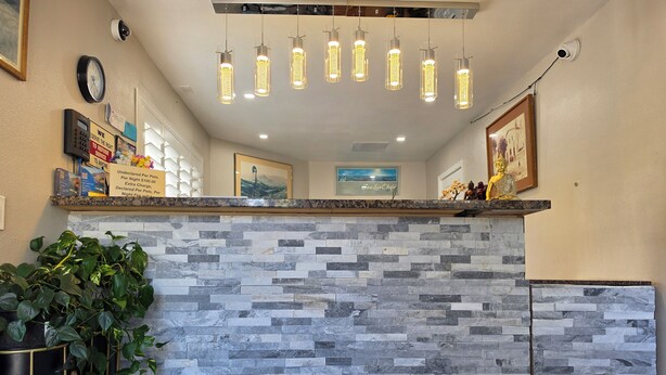 A reception area with a stone wall, a plant, a clock, and a framed picture on the wall. - San Luis Inn And Suites (San Luis Obispo)