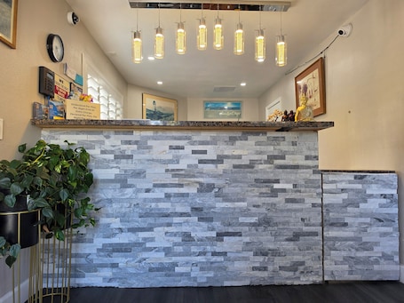 A reception area with a stone wall, a plant, a clock, and a framed picture on the wall.. San Luis Inn And Suites