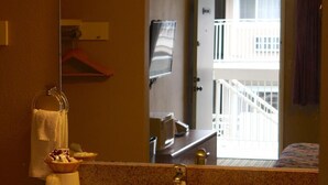A bathroom with a sink, mirror, towel rack, and a view of a balcony. - San Luis Inn And Suites (San Luis Obispo)