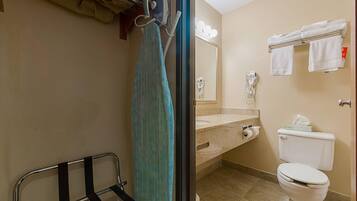 A bathroom with a shower, a towel rack, a toilet, and a sink with a mirror.