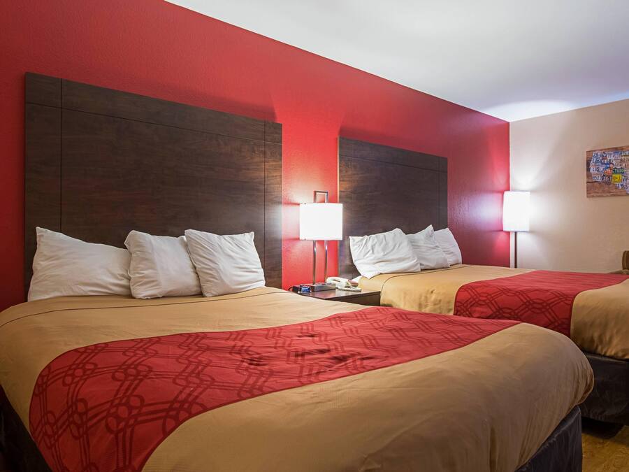 Habitación de hotel con dos camas, paredes rojas y un cuadro con un mapa en la pared.