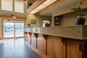 A reception desk with a wooden finish, a potted plant, and a framed picture on the wall. - Econo Lodge Buckley Bonney Lake (Buckley)
