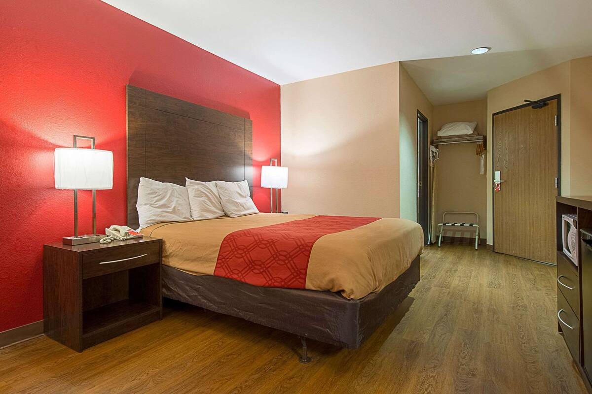 Une chambre d’hôtel avec un lit, des lampes de chevet, une table de chevet, un plancher en bois et une porte donnant sur une salle de bain.