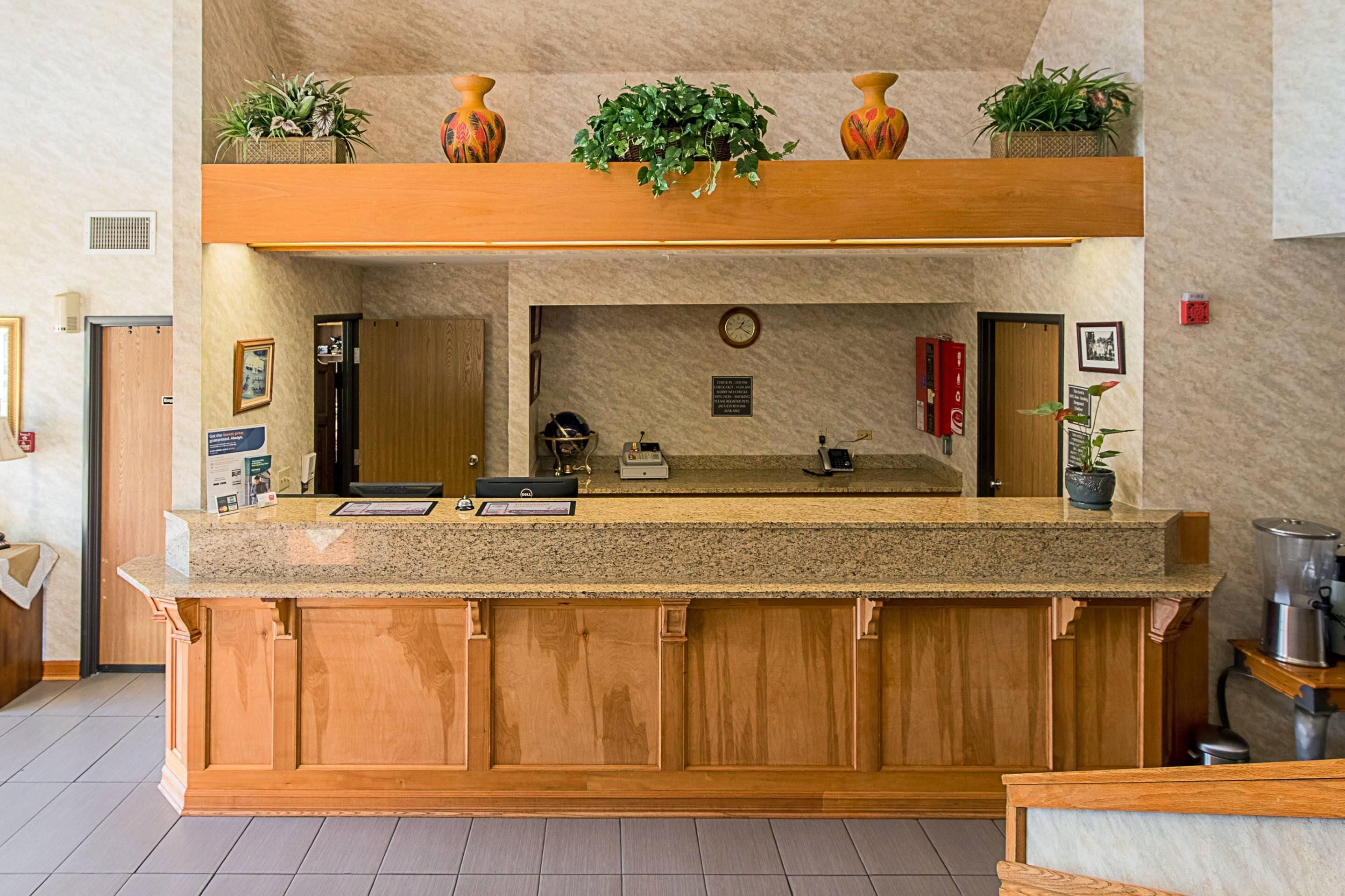 A reception desk with a wooden counter, a clock, and a sign indicating check-in times.