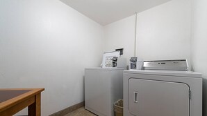 Une buanderie équipée de deux machines à laver, d’un sèche-linge et d’une petite poubelle.