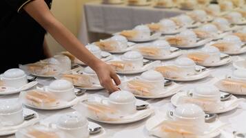 A table set with multiple white teacups and saucers, arranged neatly in rows.