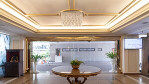 A lobby with a round table, a chandelier, and potted plants. - Forum Park Hotel (Bangkok)