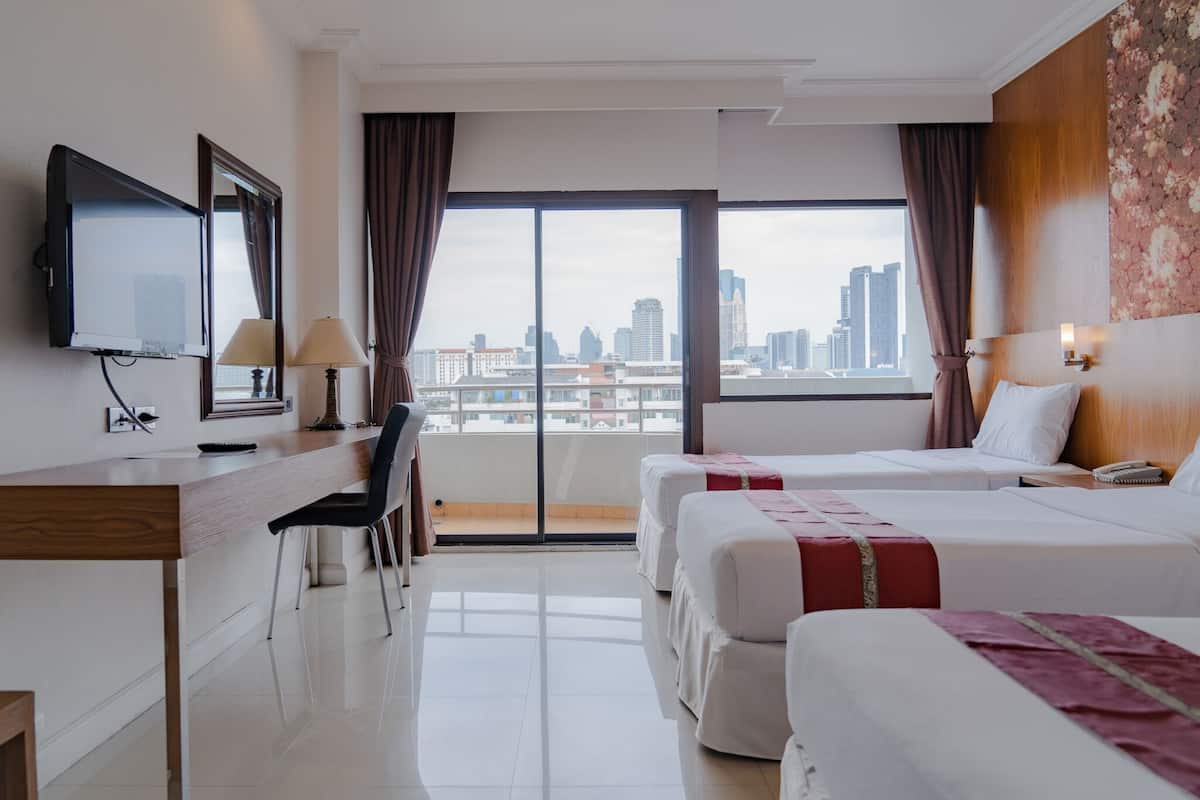 Habitación de hotel con dos camas, un escritorio, una silla, un televisor y vistas a la ciudad.