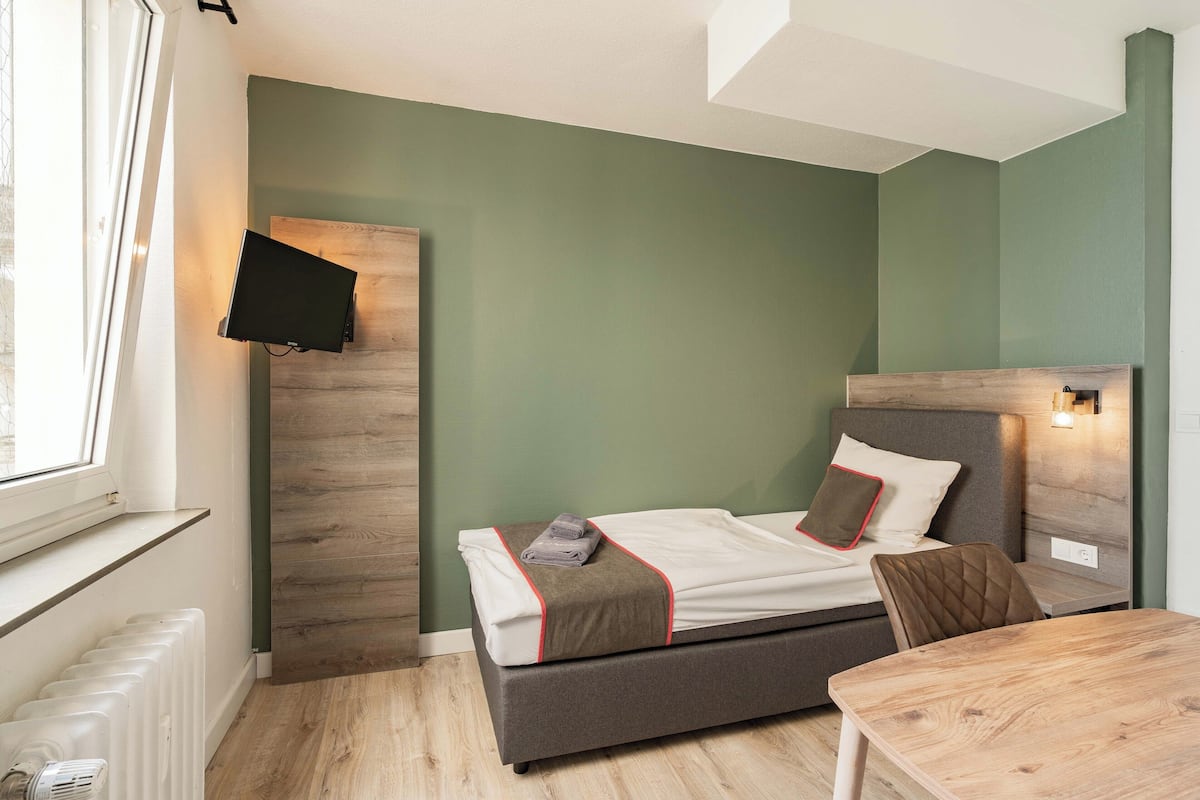 A bedroom with a bed, a table, and a chair.