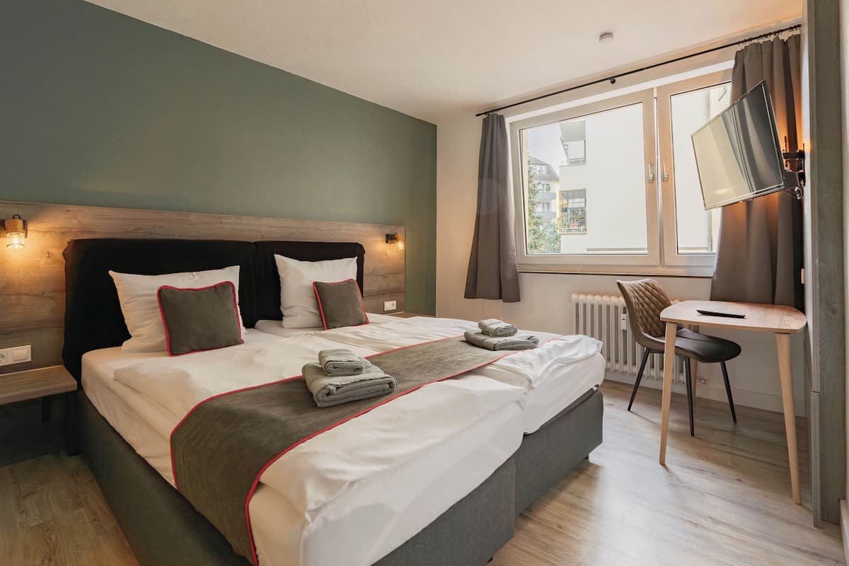 A modern hotel room with a large bed, bedside tables, a desk, and a chair.