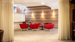 Un espace repas moderne avec des chaises rouges et une table, des murs recouverts de panneaux en bois et des spots encastrés au plafond.