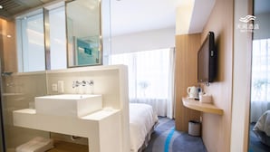A modern hotel room with a large white sink, a mirror, a flat-screen TV mounted on the wall, a bed with white bedding, and a small shelf with toiletries. - Skytel Xi'an (Xi'an)