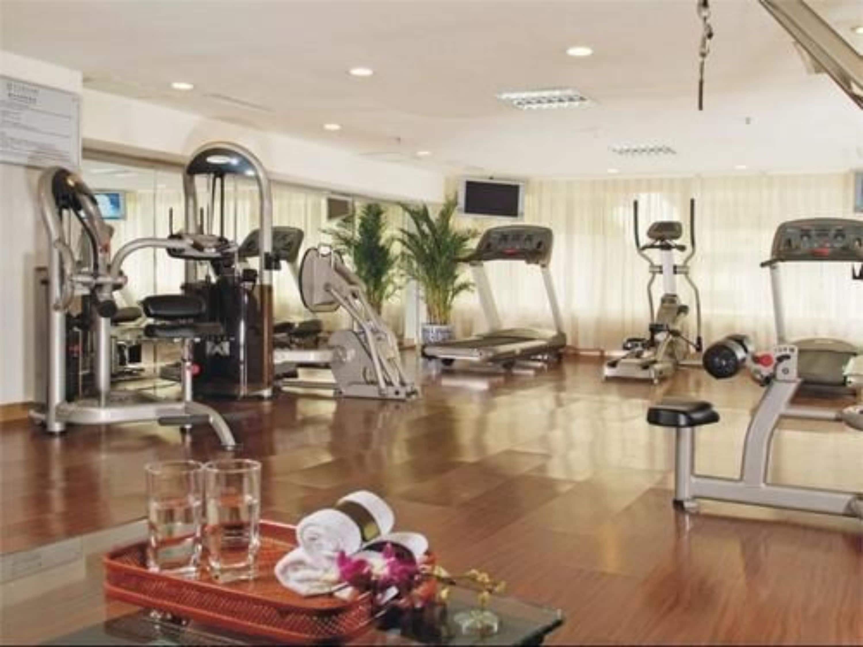 Un gimnasio con diversas máquinas de ejercicio, una cinta de correr y una estación de agua.