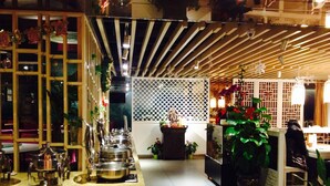 A restaurant interior with a long counter, multiple tables, and potted plants. - Skytel Xi'an (Xi'an)
