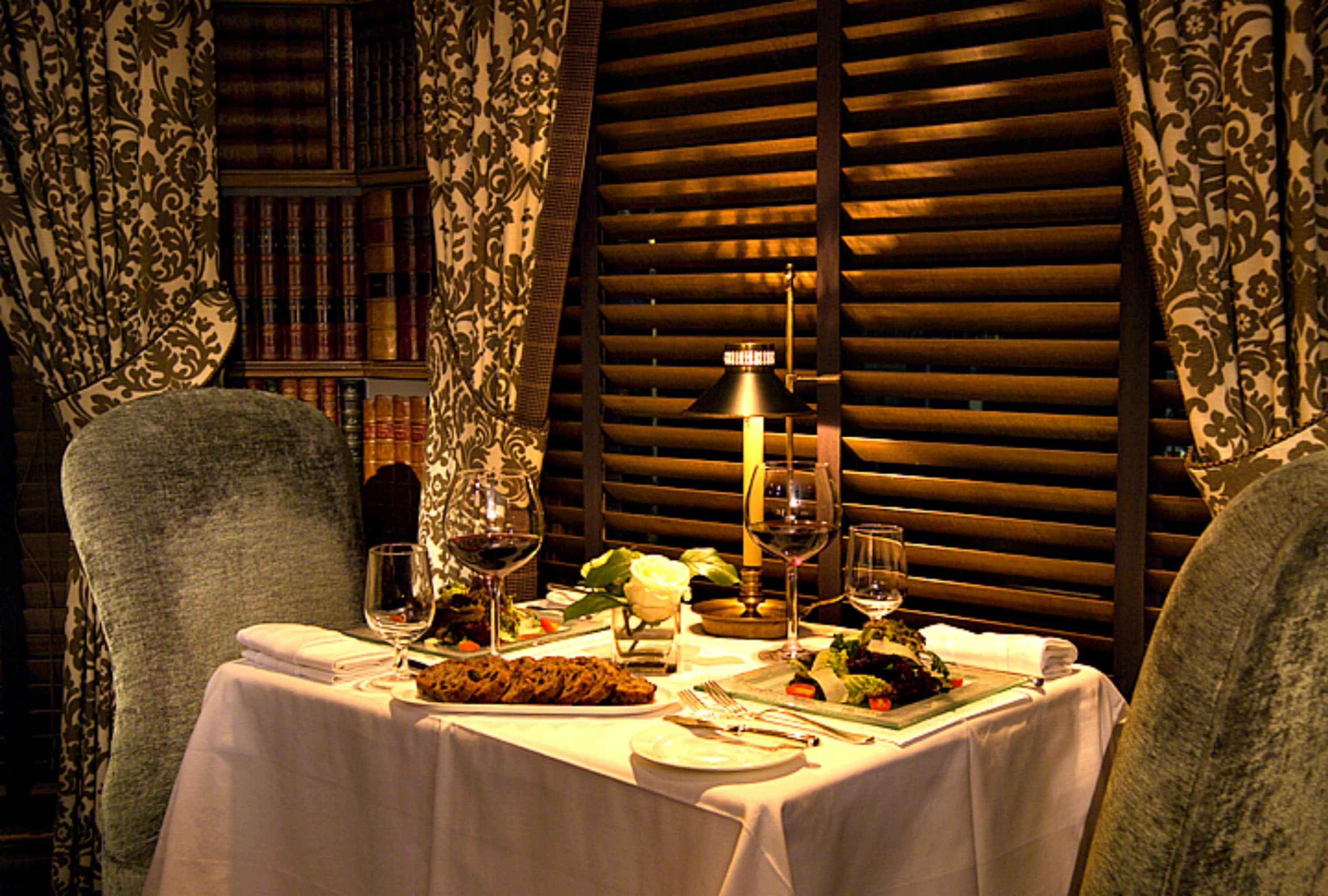 Una mesa de comedor dispuesta con platos, cubiertos, copas de vino y una vela.