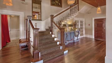 A grand staircase with wooden railings and a patterned carpet, leading to a landing with a glass coffee table and decorative items.