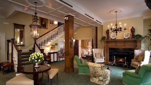 A spacious living room with a grand staircase, a fireplace, and a variety of seating options. - Bernards Inn (Bernardsville)