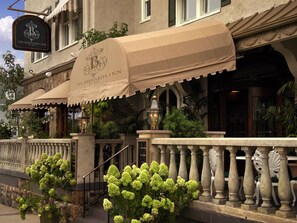 A hotel facade with a classic architectural style, featuring a large marquee sign, a covered entrance, and a stone balustrade.
