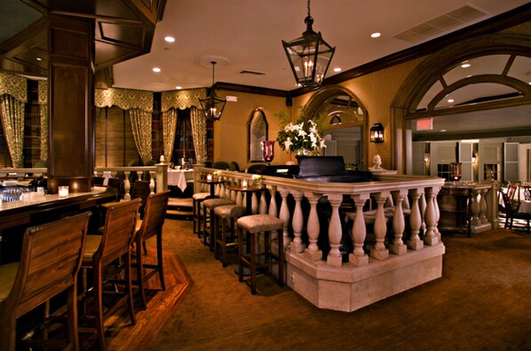 A bar area with a stone counter, wooden chairs, and a hanging light fixture. - Bernards Inn (Bernardsville)