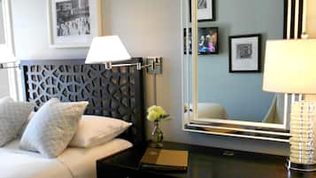 Une chambre d’hôtel avec un lit, une table de chevet, un miroir et un téléviseur.