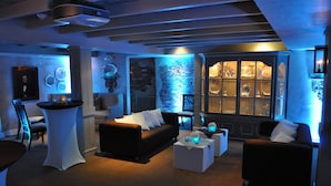 A modern living room with a black sofa, white armchairs, and a glass display cabinet. - Bernards Inn (Bernardsville)