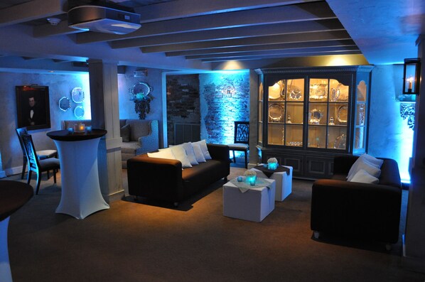 A modern living room with a black sofa, white armchairs, and a glass display cabinet. - Bernards Inn (Bernardsville)