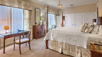 A bedroom with a four-poster bed, a desk with a lamp, a dresser, and a large mirror.