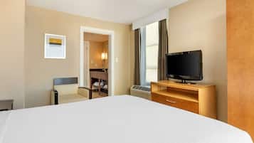 A hotel room with a large bed, a television on a wooden stand, a desk with a chair, and a wardrobe.