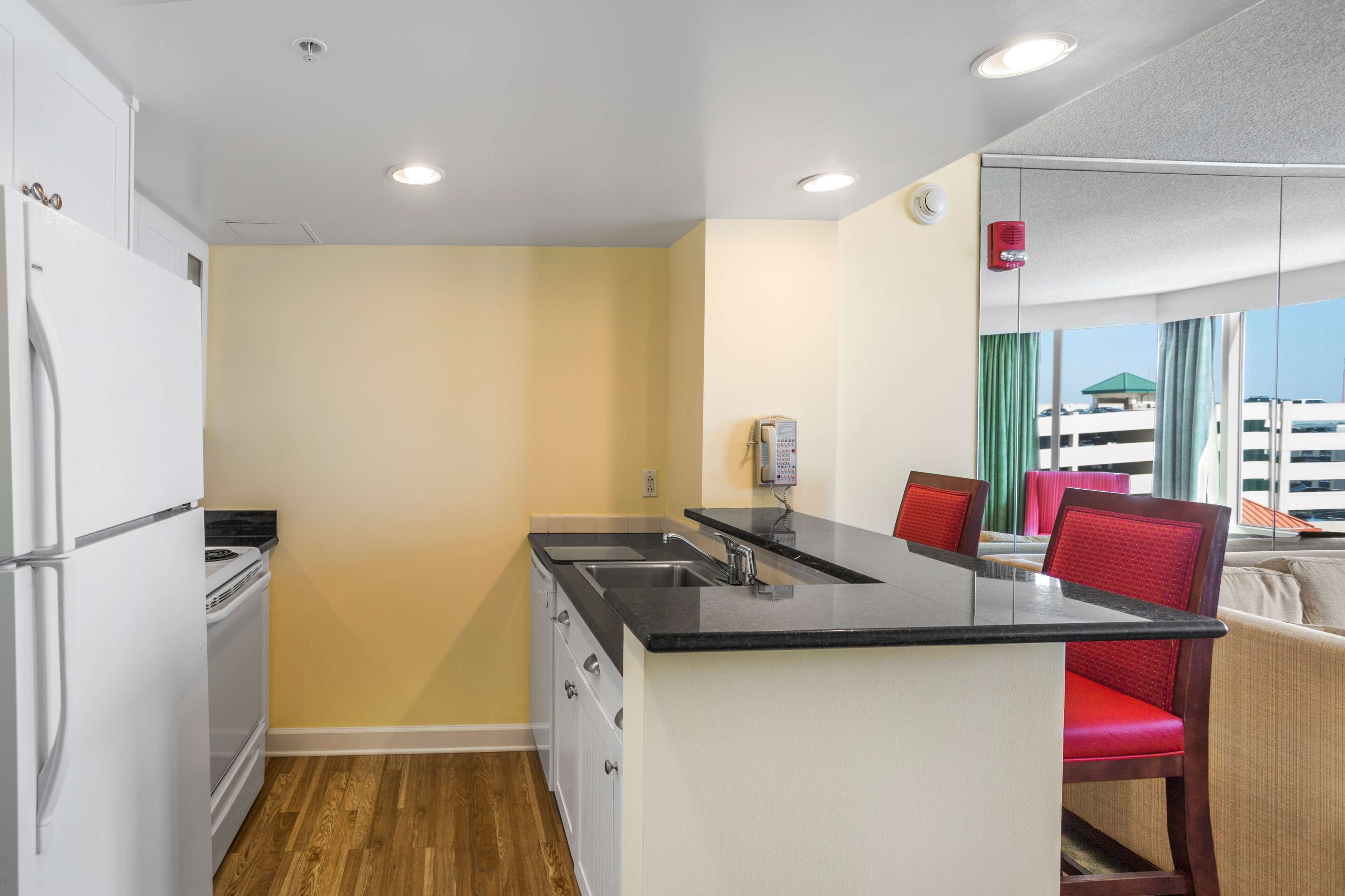 A compact kitchen with a black countertop, white cabinets, and a built-in oven.