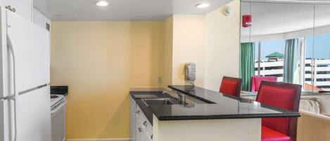A compact kitchen with a black countertop, white cabinets, and a built-in oven.