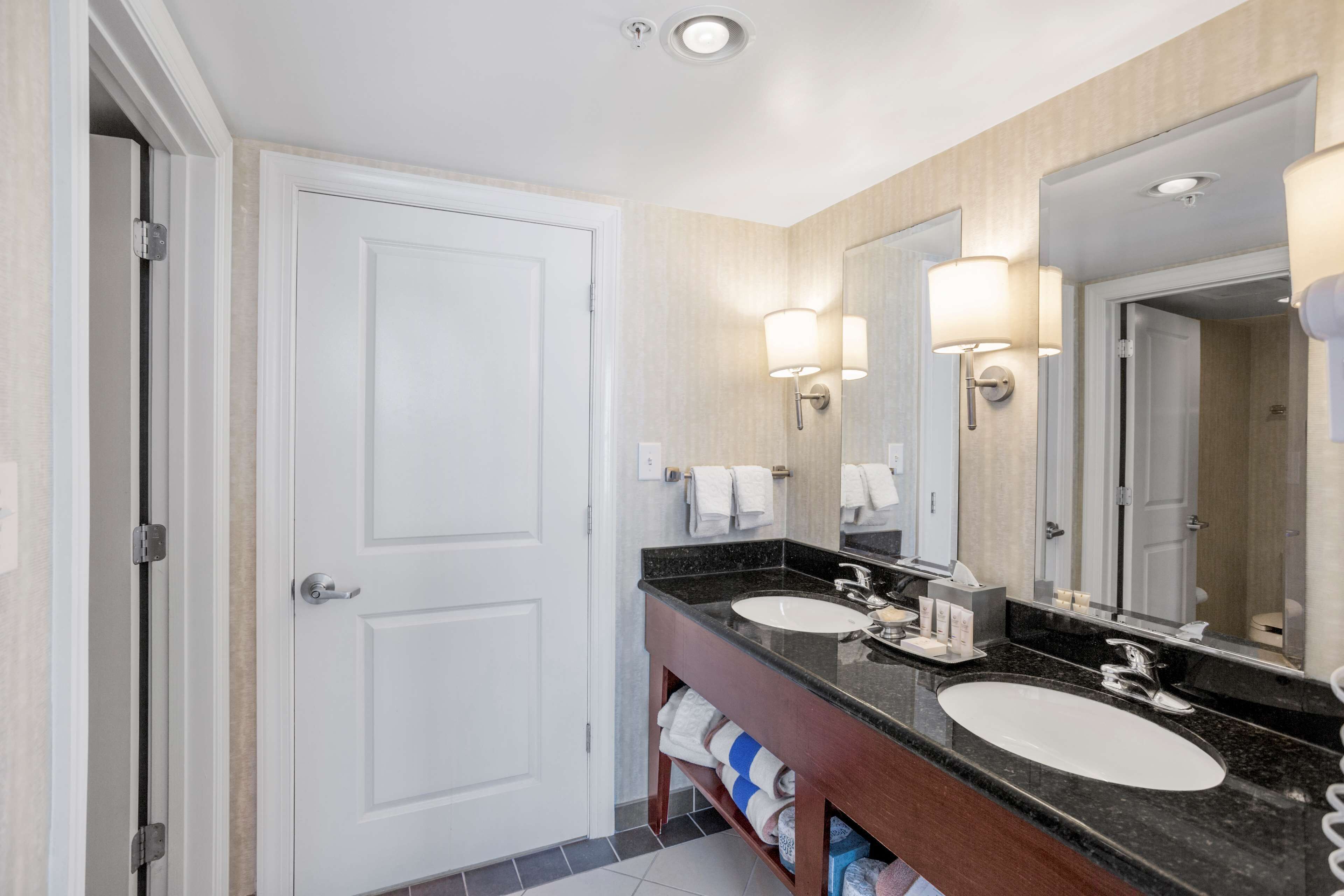 Une salle de bain d’hôtel avec deux lavabos, un grand miroir et un porte-serviettes.