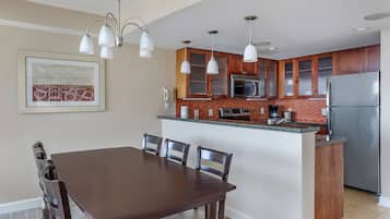 Una cocina moderna con armarios de madera, una isla central y una zona de comedor con una mesa y sillas marrones.