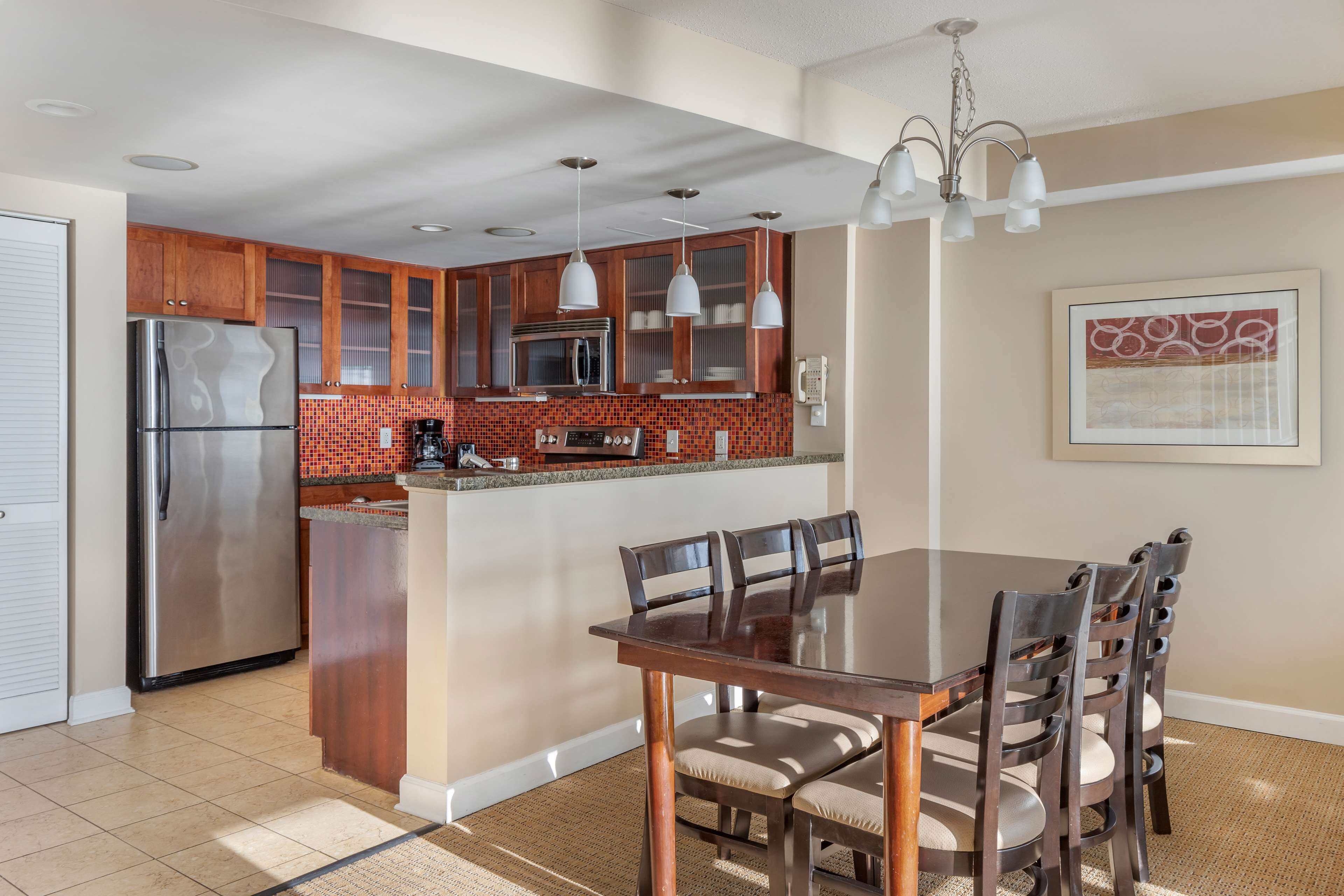 A modern kitchen with wooden cabinets, a stainless steel refrigerator, and a central island with seating.
