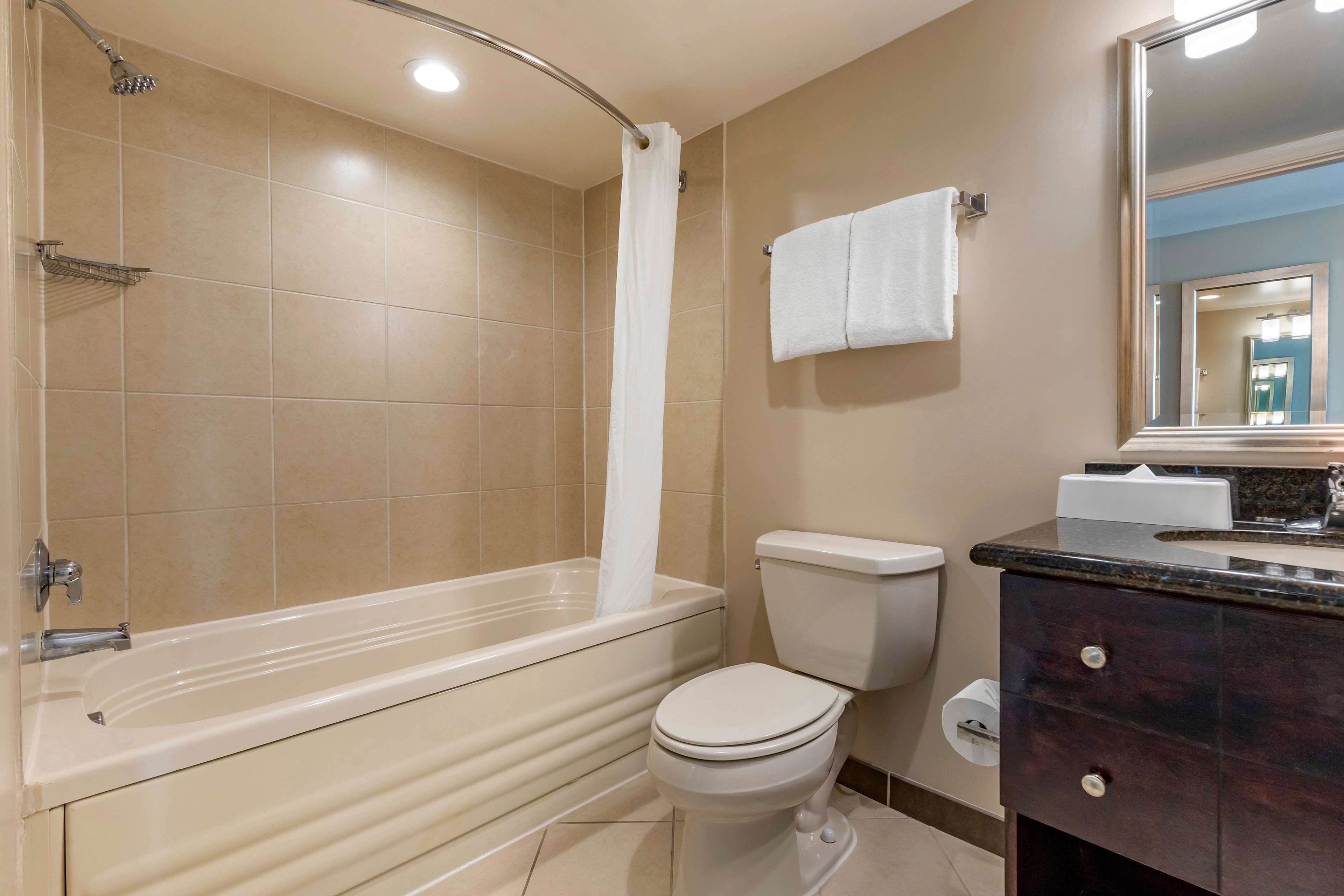 A bathroom with a bathtub, toilet, and vanity with a mirror.
