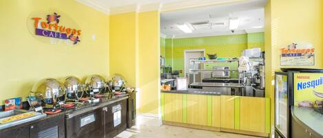Un área de cocina luminosa de color amarillo y verde, con un letrero que dice 'Tortugas Cafe' y una presentación de Nestlé Nesquik.