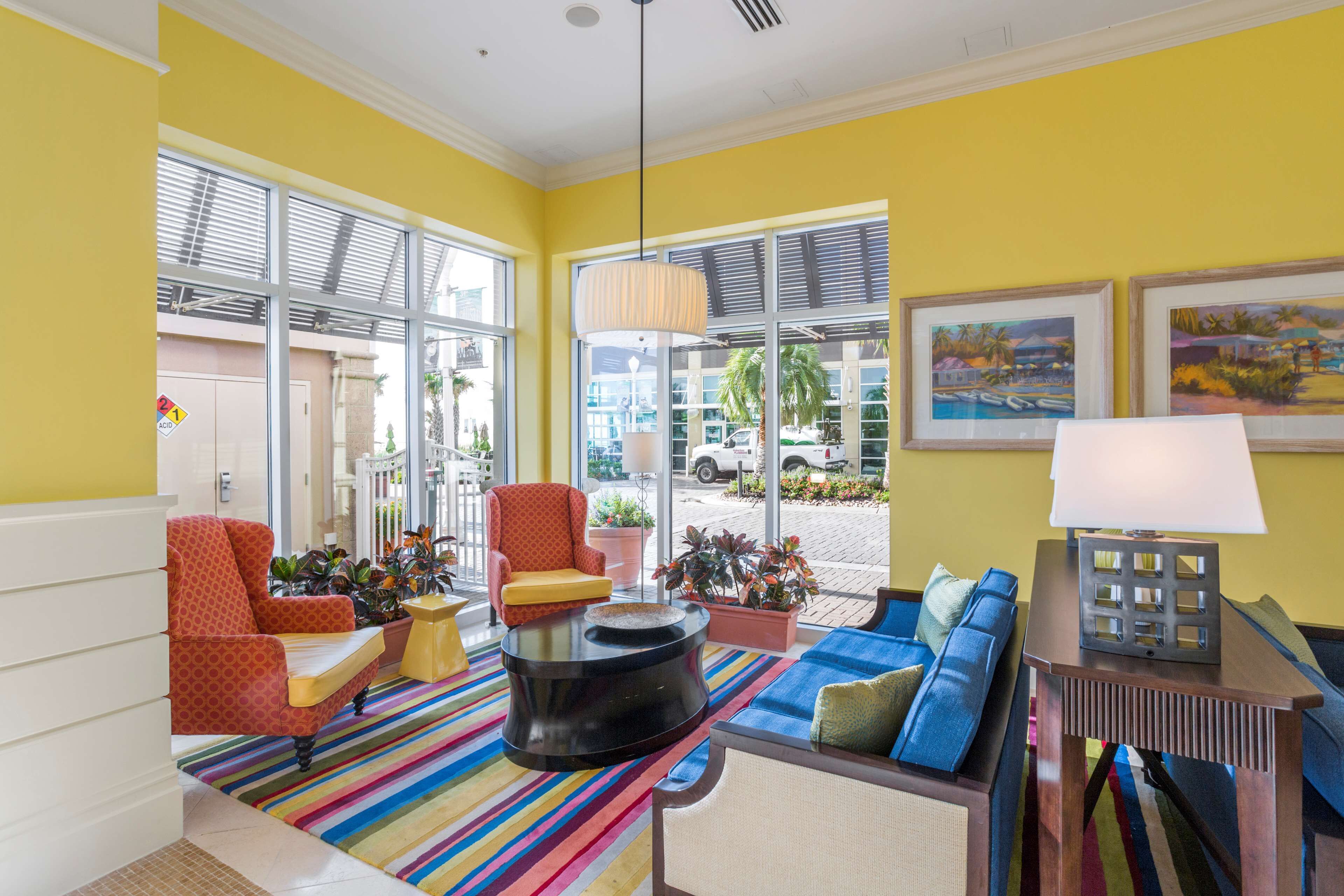 A brightly colored lobby with a striped carpet, a round coffee table, a sofa, and a chair.