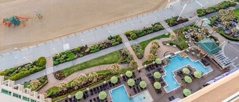 A resort with a swimming pool, lounge areas, and a beach.