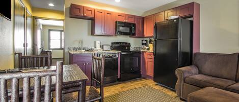 A compact kitchen with a dining area, a refrigerator, and a microwave.