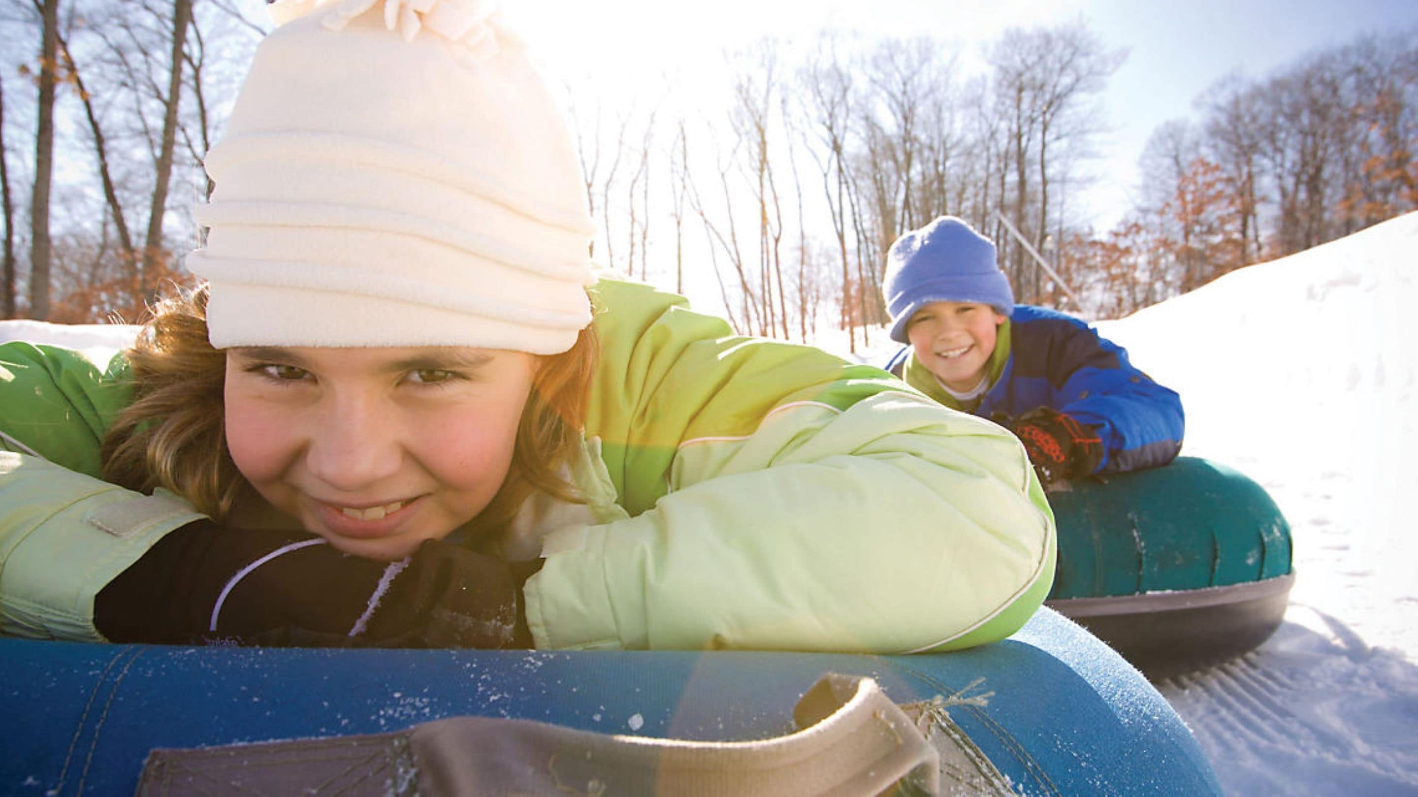 Een persoon ligt op een sled in een besneeuwde omgeving.