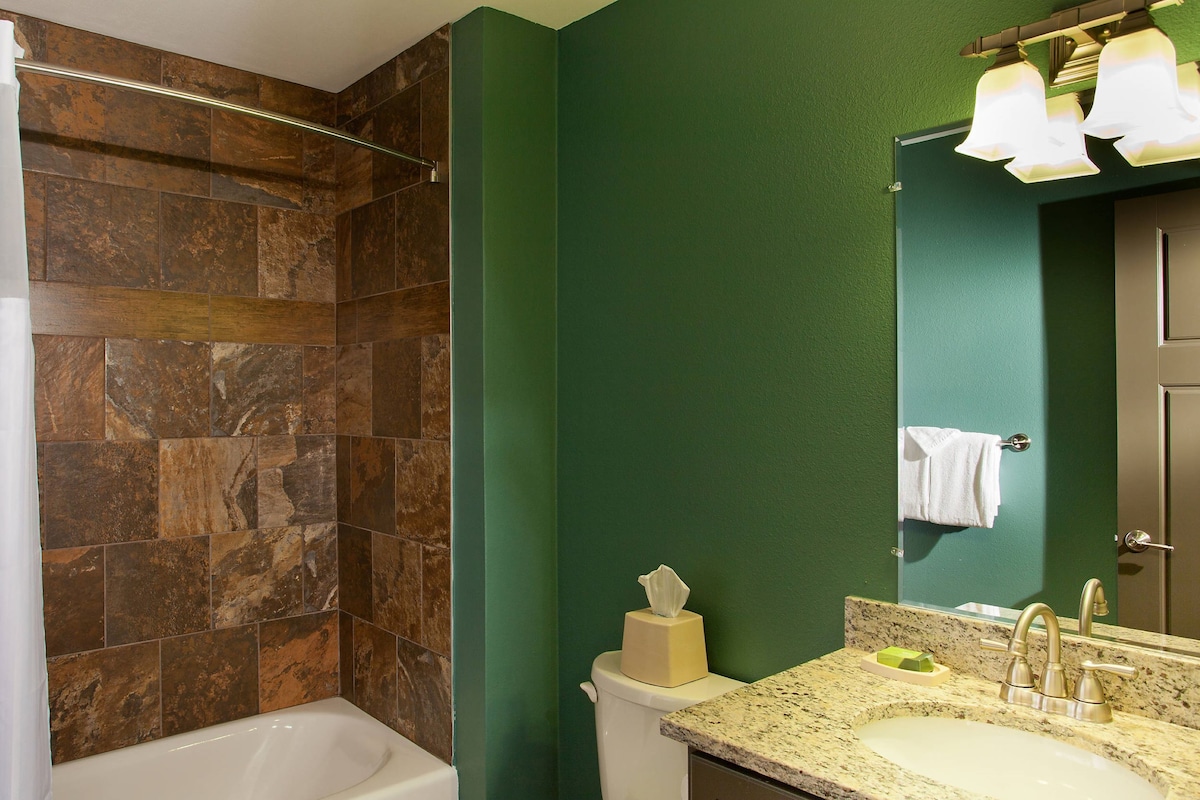 A bathroom with a bathtub, toilet, sink, and a mirror.