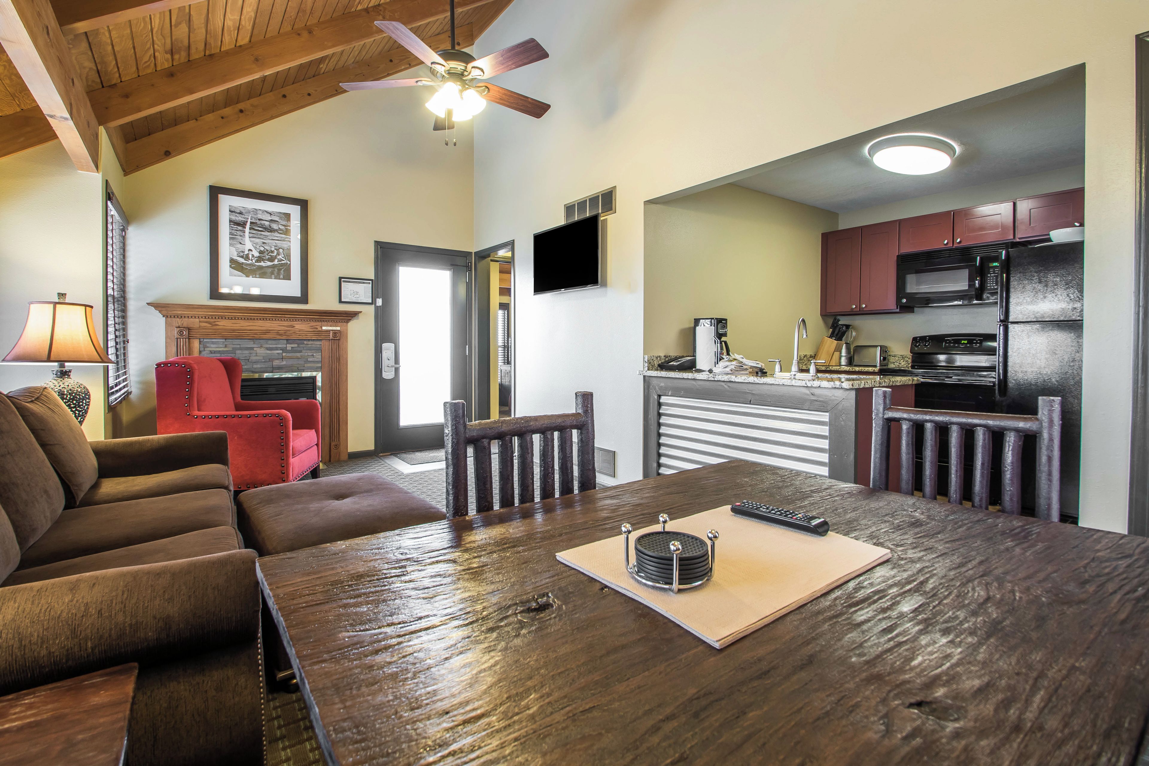 A spacious living area with a wooden dining table, a red armchair, and a ceiling fan.