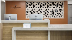 A reception desk with two computer monitors, a sign for IHG ONE REWARDS, and a wall with geometric patterns.
