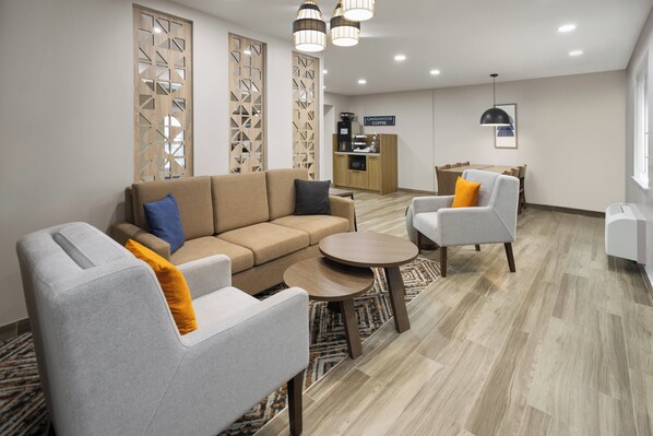 Een moderne woonkamer met een bank, fauteuils, een koffiehoek en een eettafel.