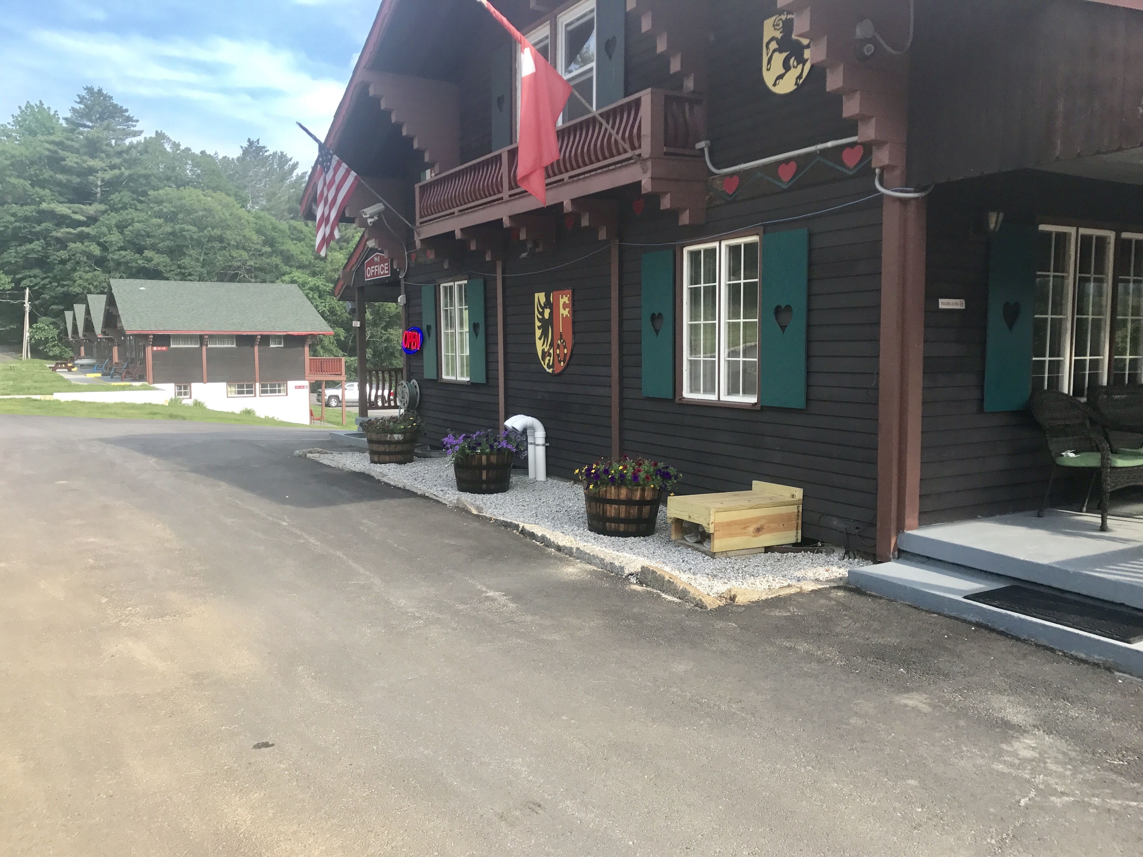 Un chalet avec une façade en bois, des volets verts et un balcon surmonté d’une marquise rouge.