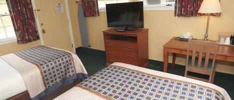 Une chambre d’hôtel avec deux lits, un téléviseur posé sur un meuble en bois, un bureau avec une chaise et une fenêtre avec des rideaux.